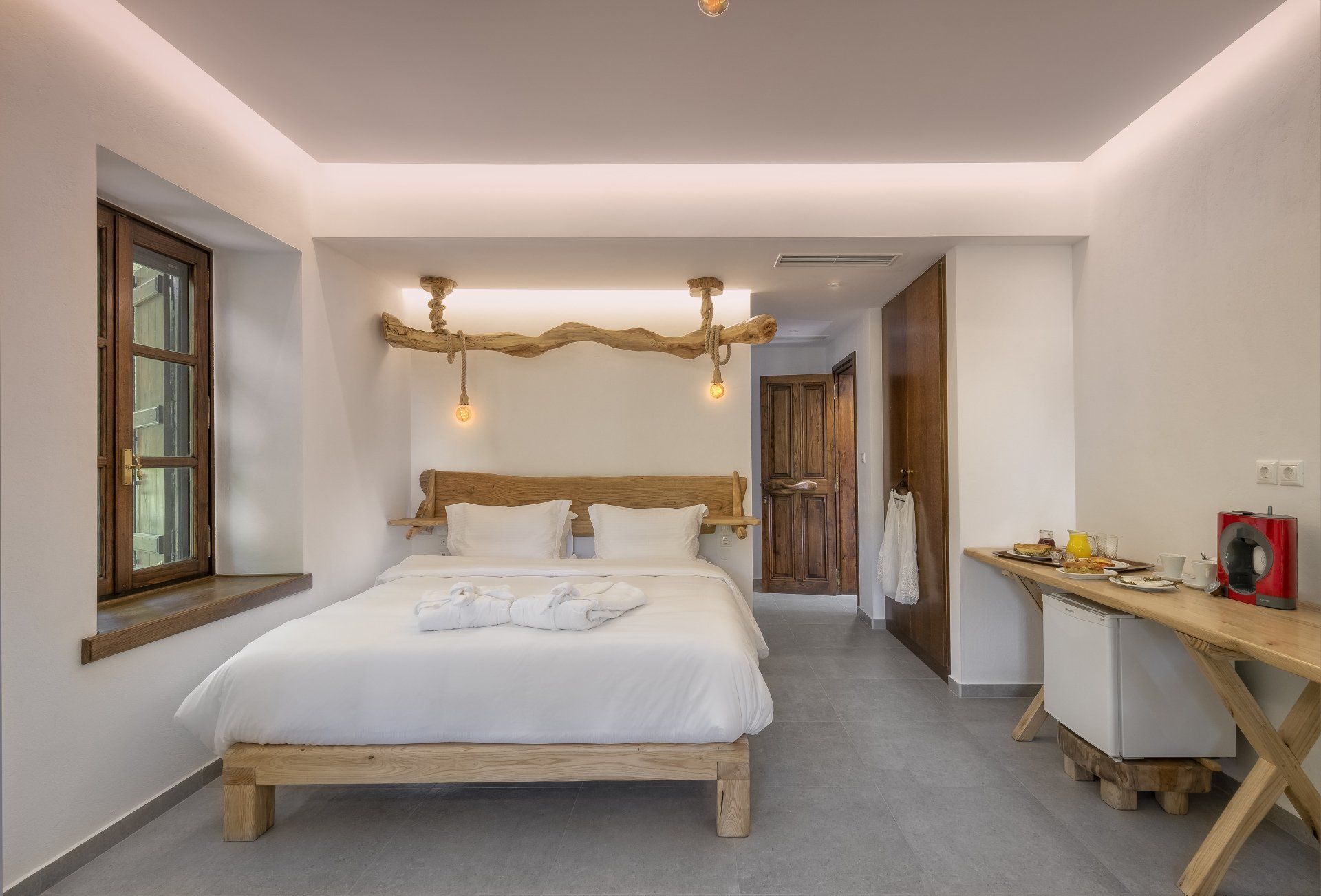 Bedroom with a bed, small table, window, and wood accents. Bright interior.