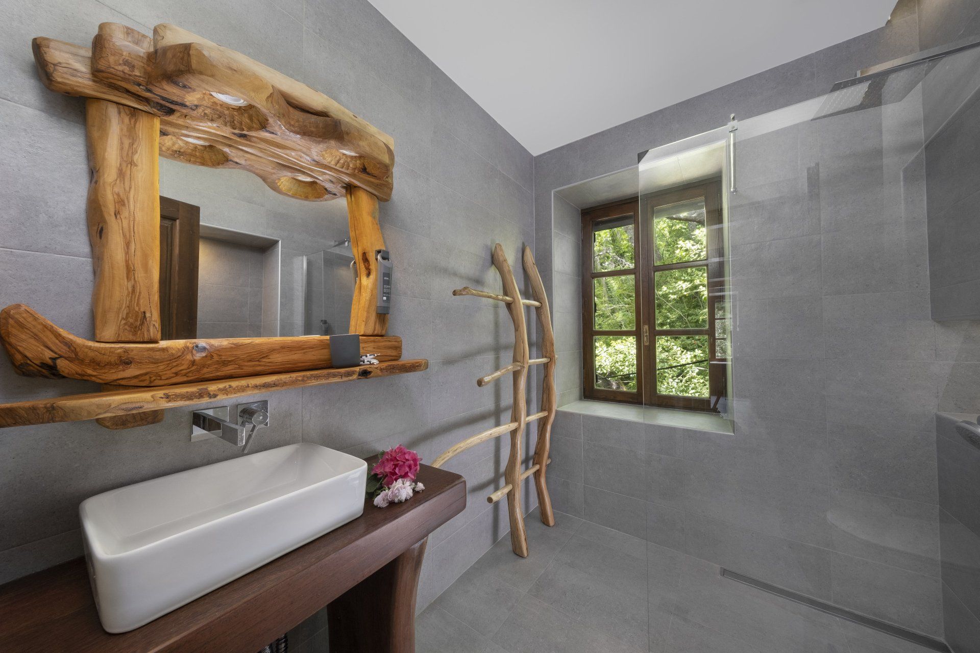 Bathroom with a rustic wooden mirror frame, a white sink, and a wooden towel rack.