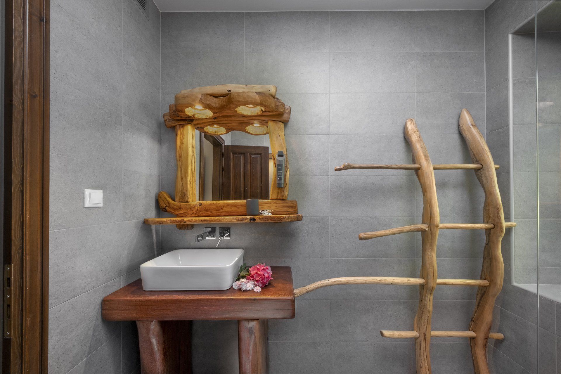 Bathroom with rustic wooden accents: vanity, mirror, towel rack, gray walls.