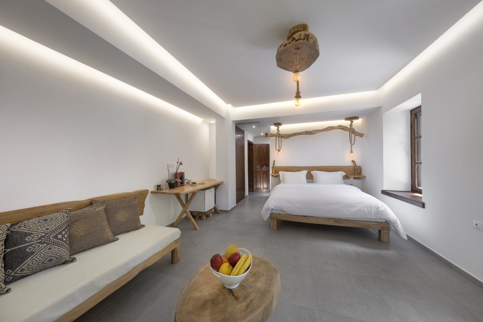 Cozy hotel room with light wood furniture, white walls, and a large bed. Natural wood accents and modern lighting.