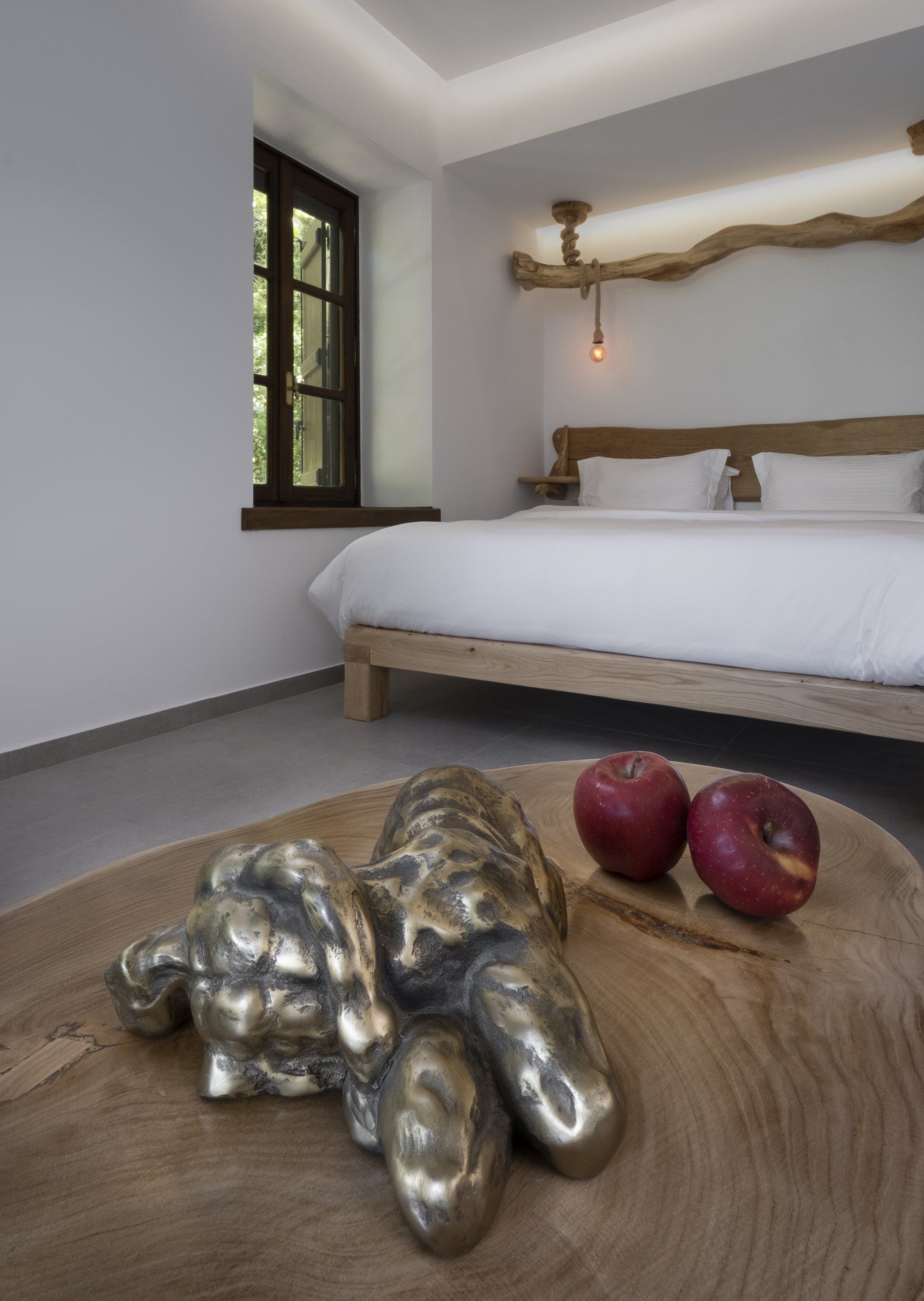 Bedroom with bed, bronze sculpture, apples, window, and wood accents.