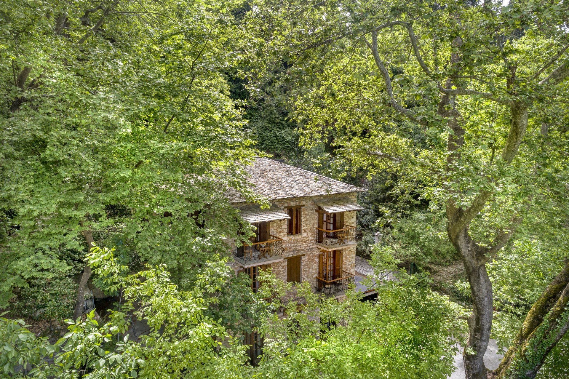 Stone house nestled in lush green trees.