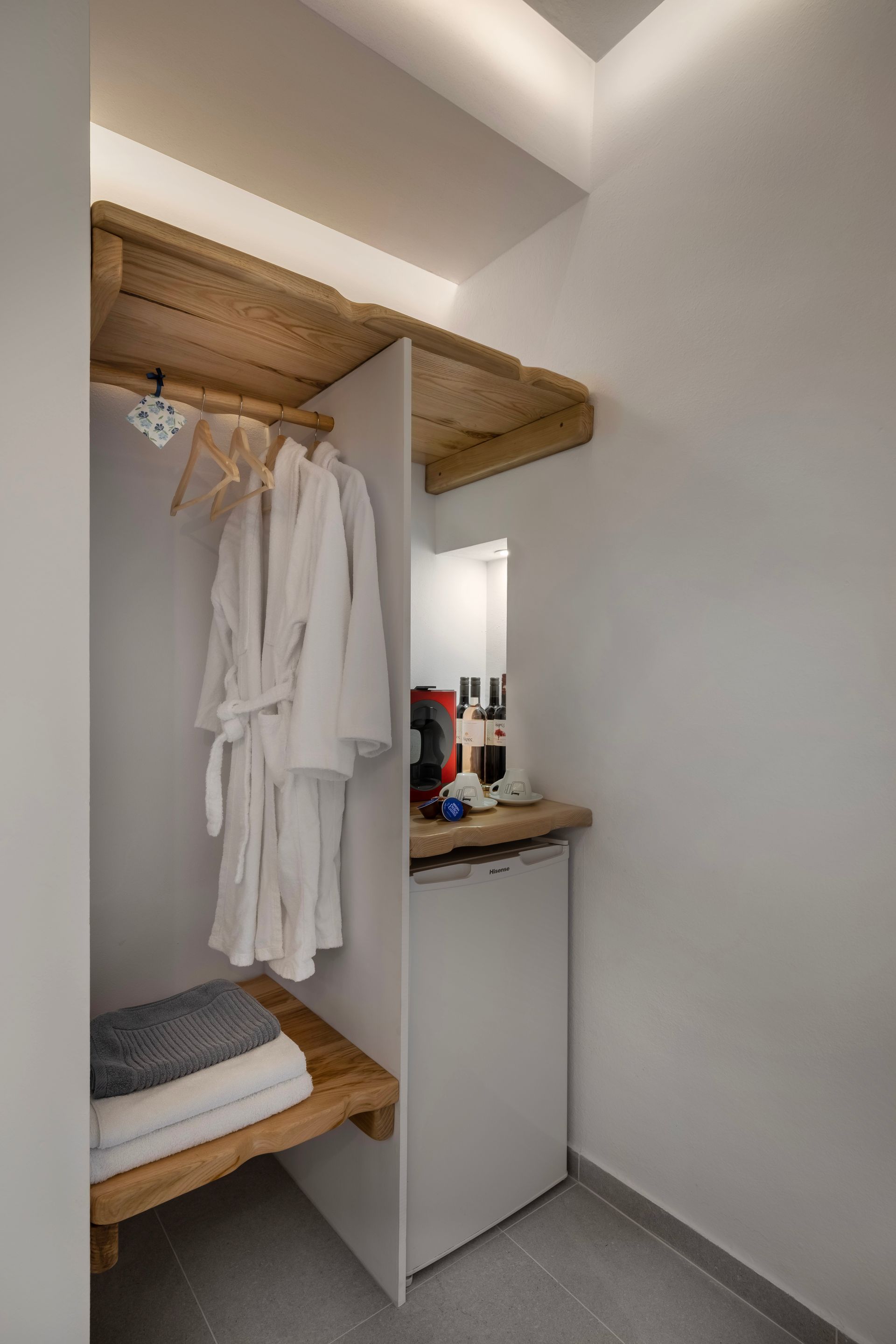 Closet with white walls, robes, towels, and a mini-fridge.