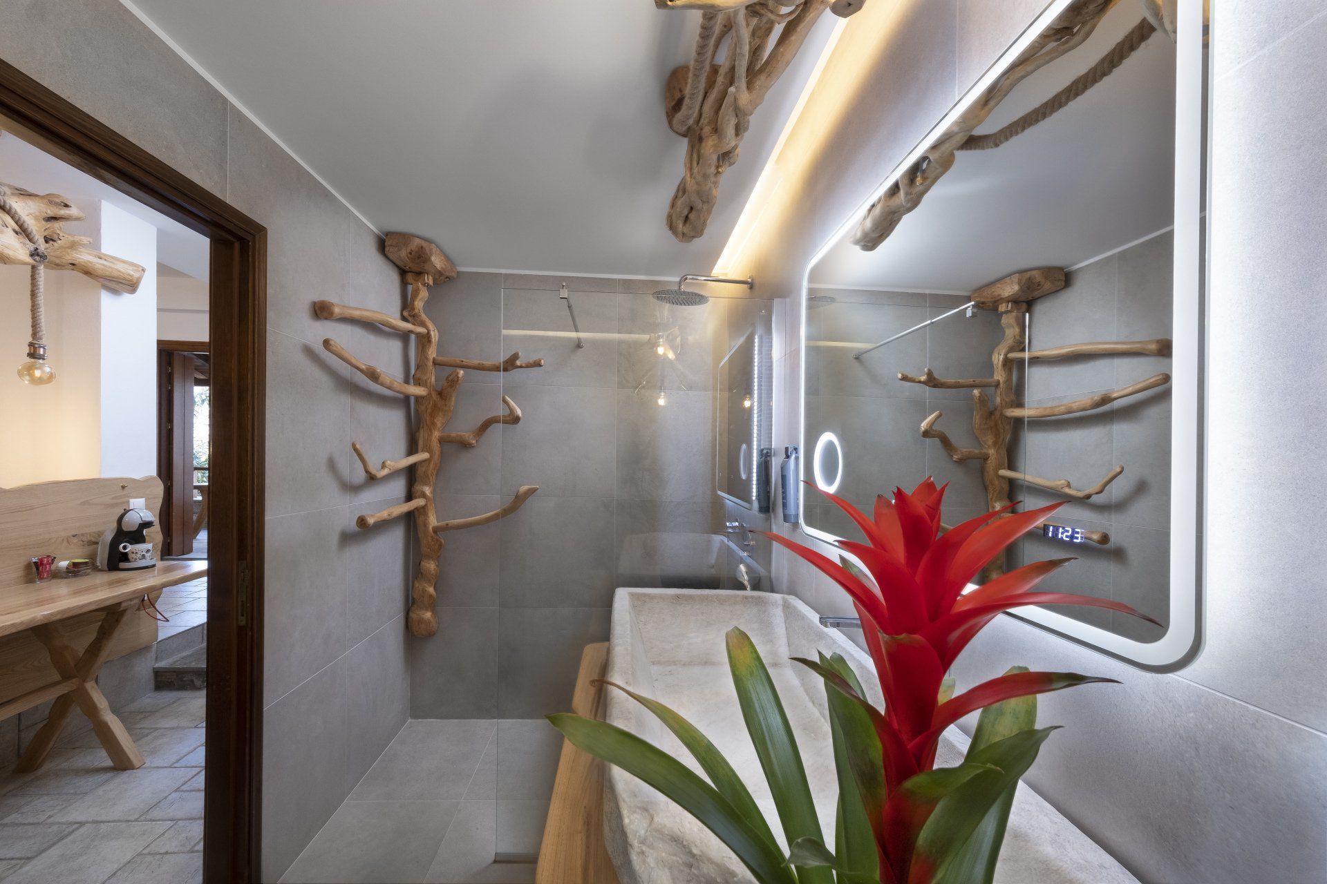 Bathroom with driftwood accents, large mirror, and red tropical flower.