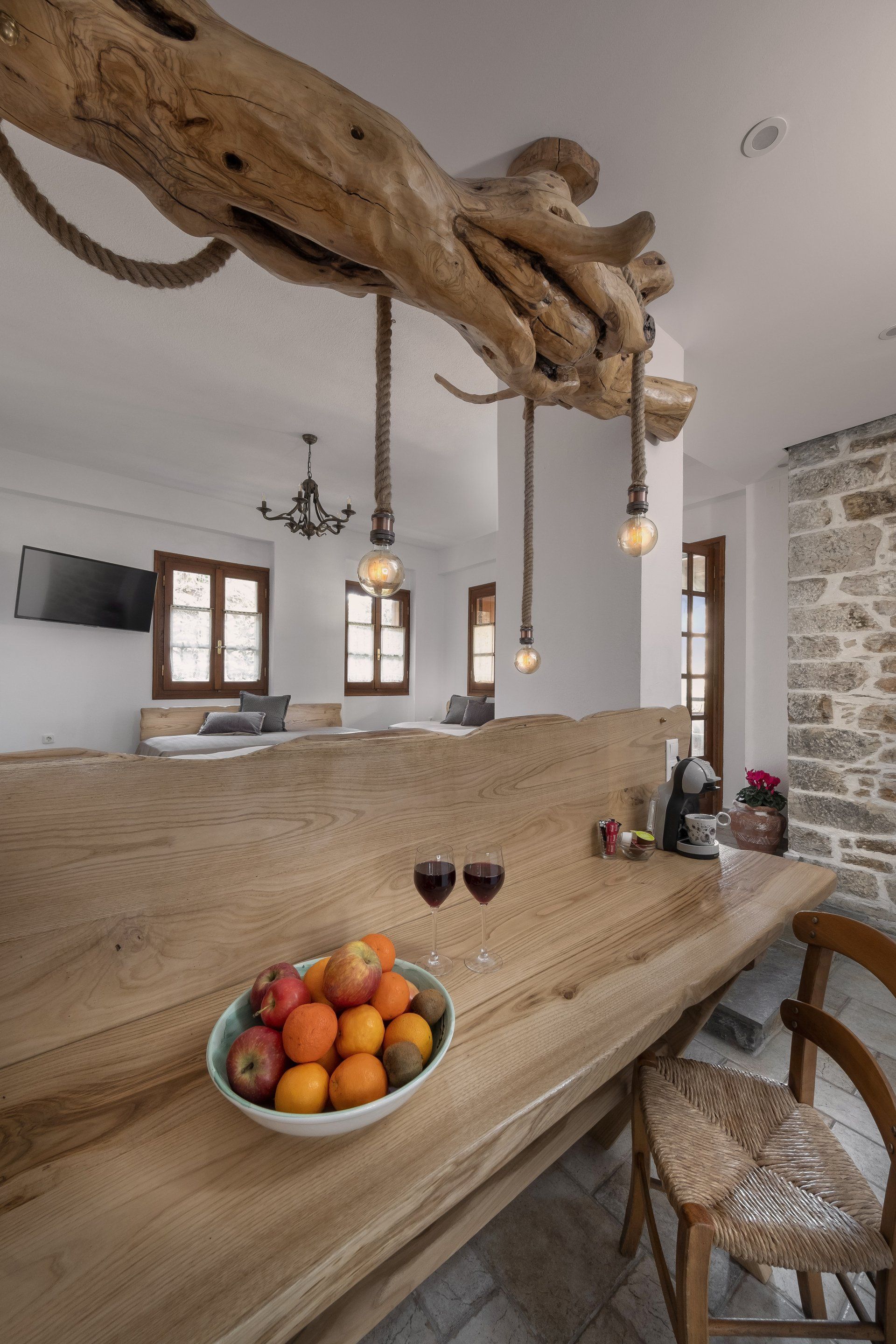 Wooden bar with fruit bowl and wine glasses, rustic decor, tree branch light fixture.