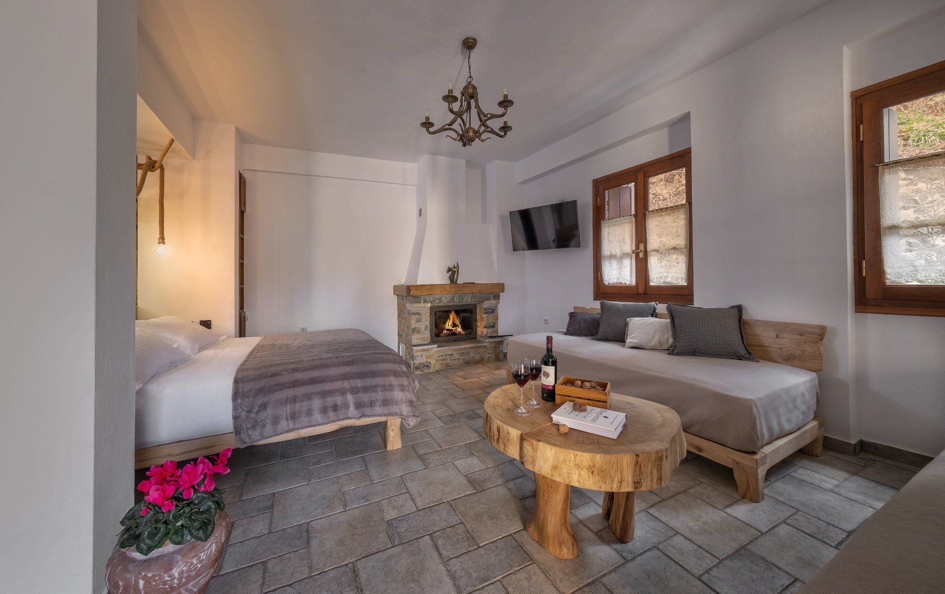 Cozy hotel suite with fireplace, sofa, bed, and wooden accents.