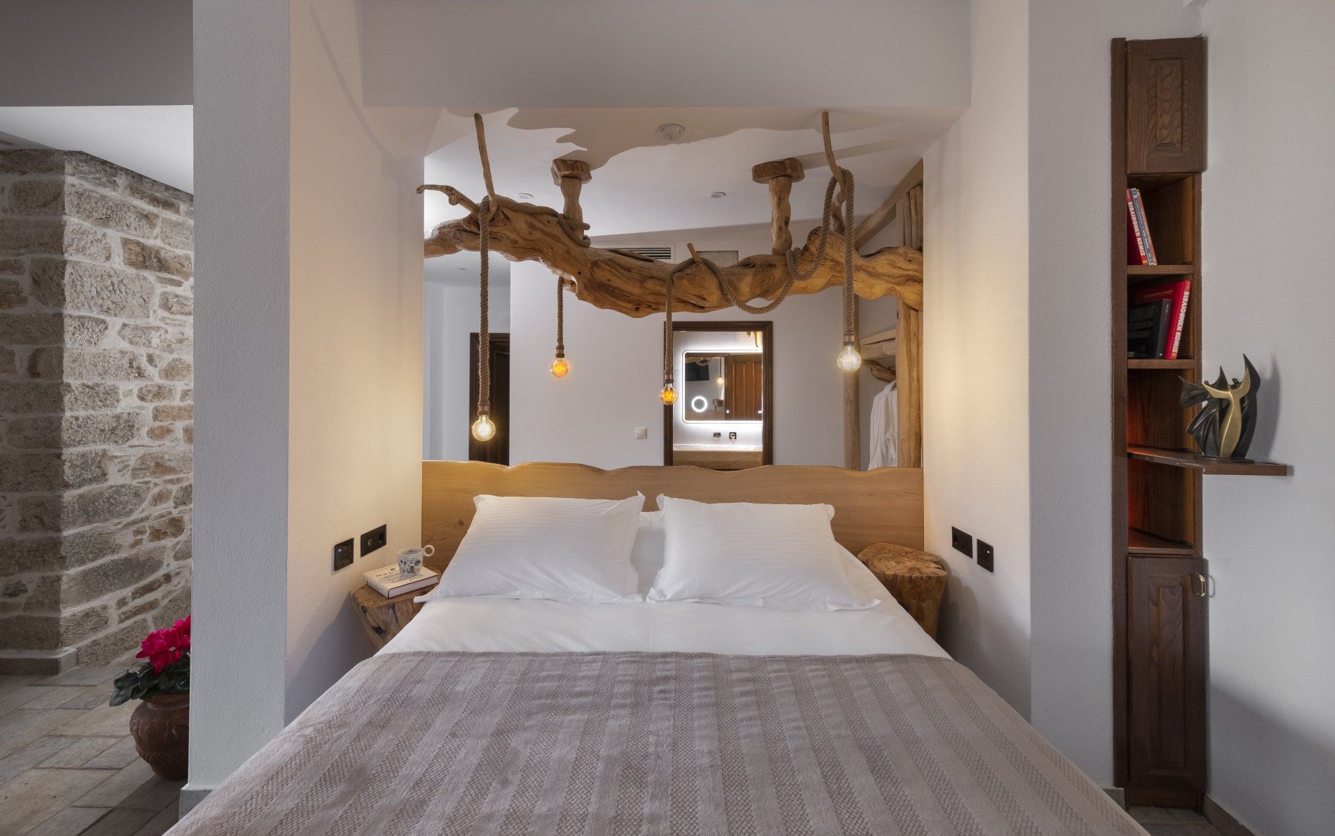 Bedroom with wooden headboard, hanging branch, and open doorway to bathroom.