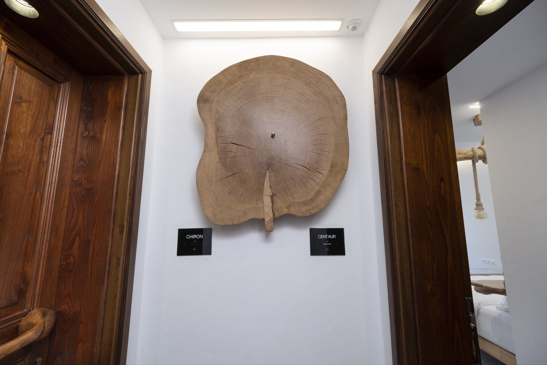 Wooden slab art piece on white wall between two wooden doorways.