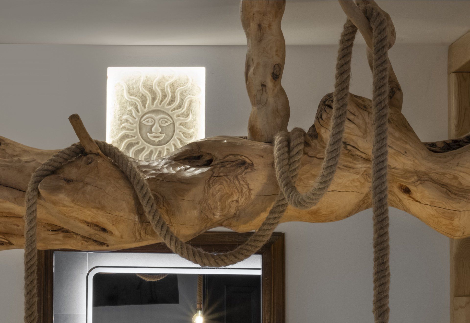 Wooden beam with rope and sun-shaped wall art.