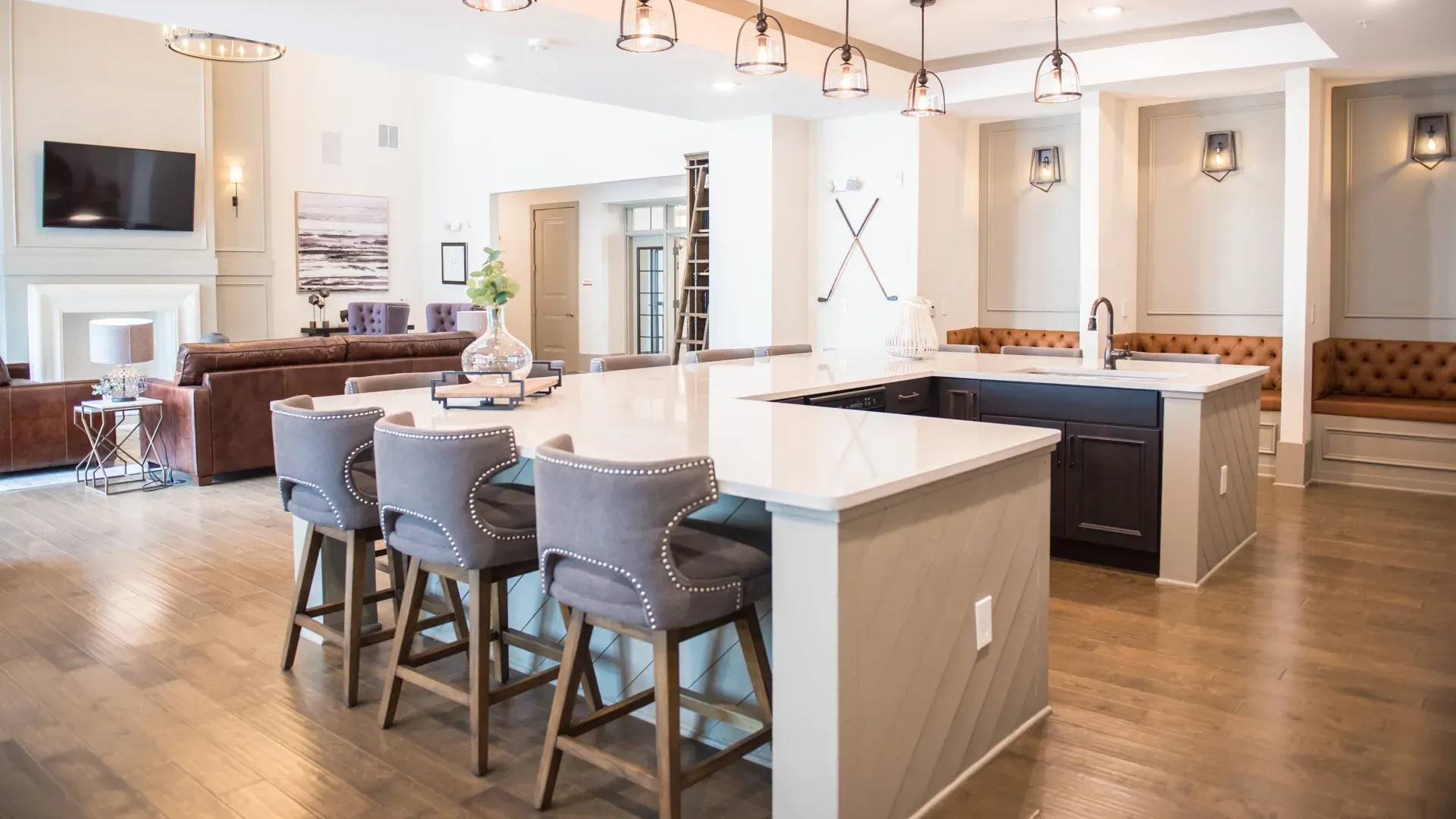 Modern kitchen island with bar stools in a communal lounge area with leather seating and a TV.