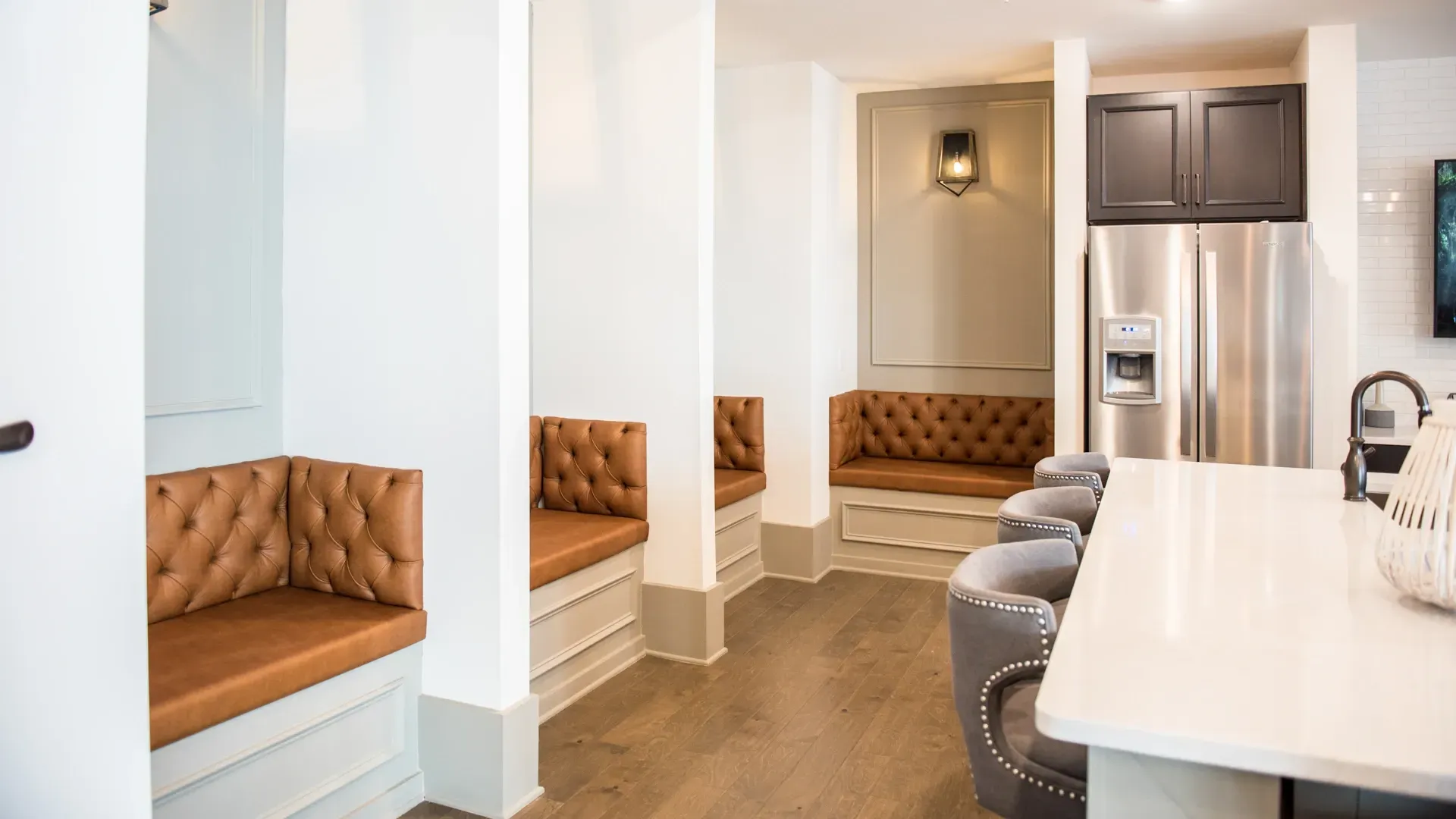 Community lounge with tufted brown seating and a modern kitchen island.