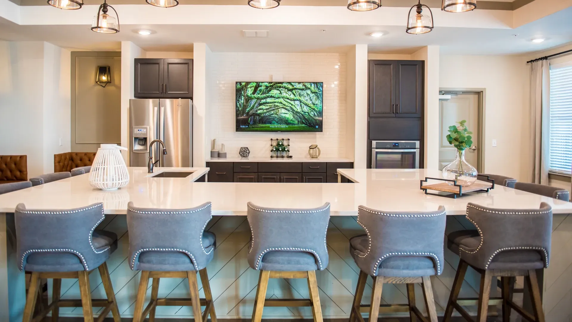 Modern kitchen island with bar stools and a TV mounted on the wall.