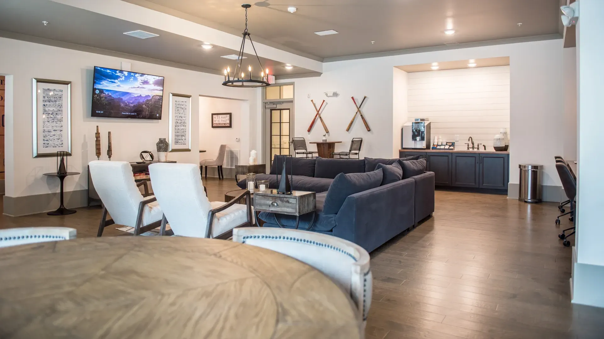Comfortable lounge area with large sofa, chairs, coffee station, and a TV.