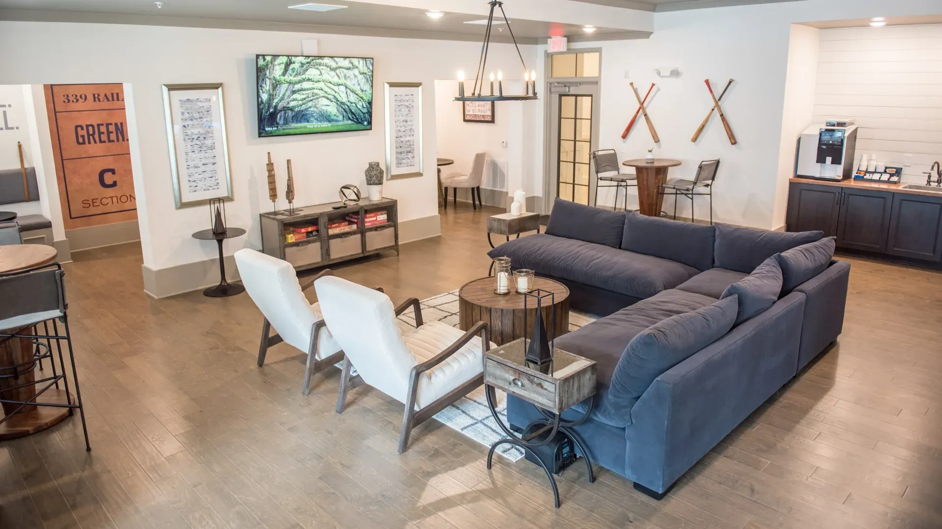 Communal lounge area with large sectional sofa, coffee table, seating, and beverage station.