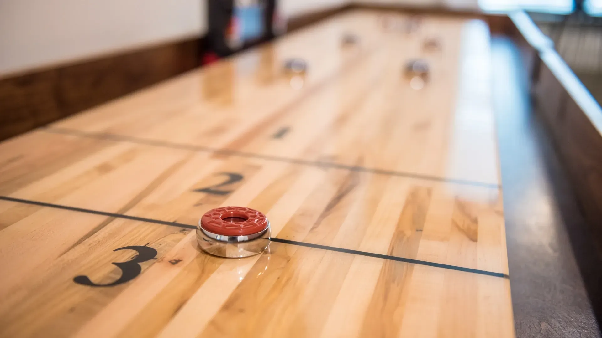 Close-up of a shuffleboard table with a red puck.