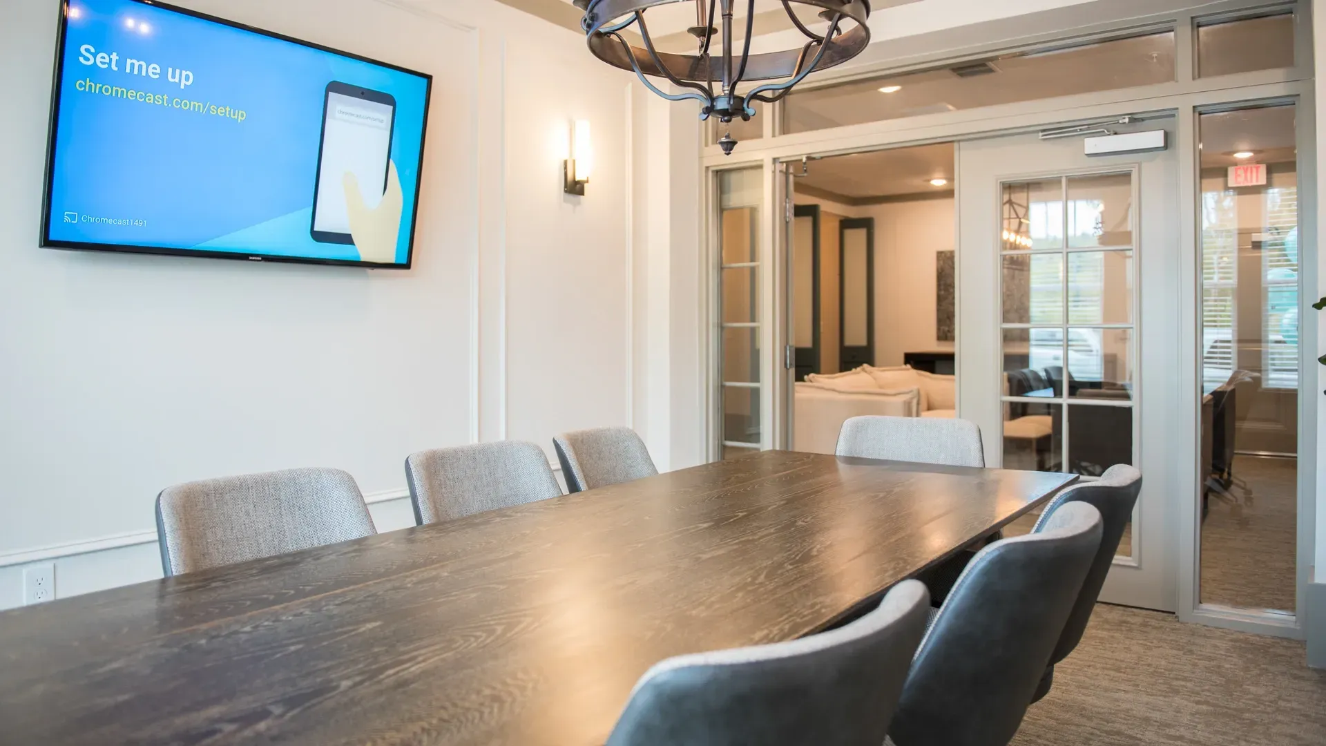 Conference room with a large table and chairs, and a TV screen displaying Chromecast setup.