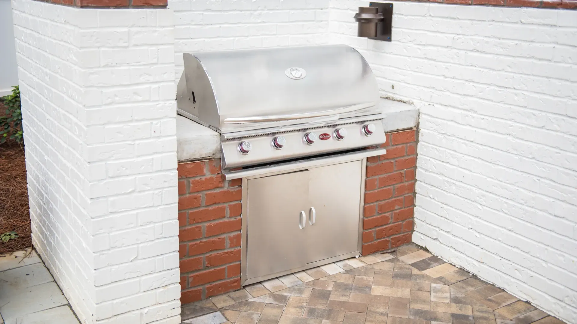 Built-in outdoor grill with stainless steel hood and storage cabinet.