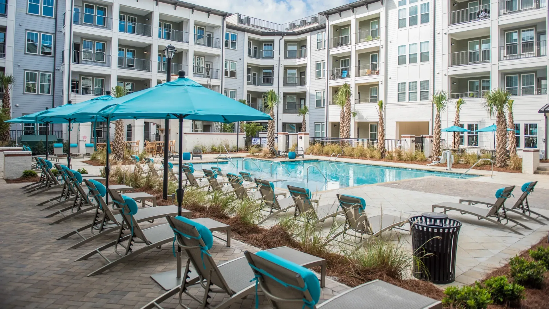Resort-style swimming pool with lounge chairs and umbrellas.