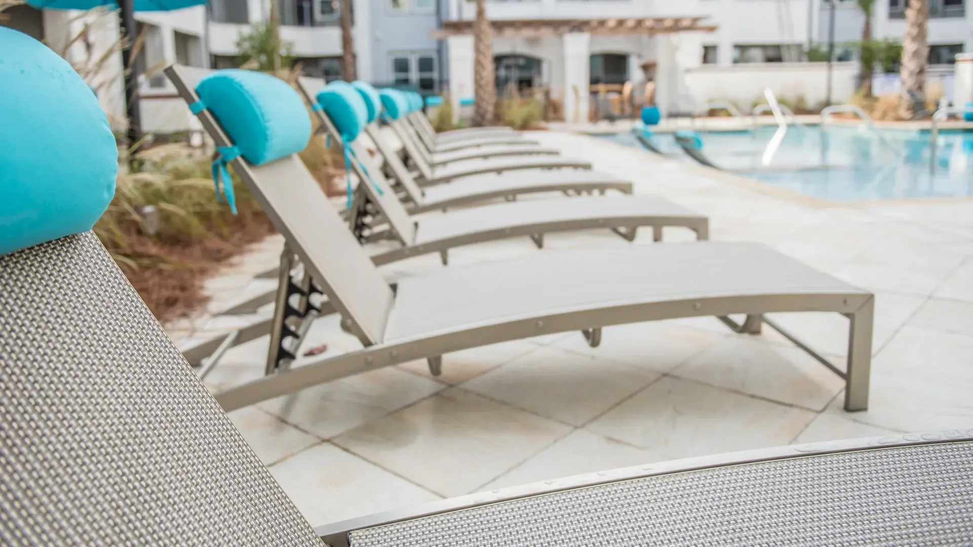 Row of lounge chairs by an outdoor swimming pool