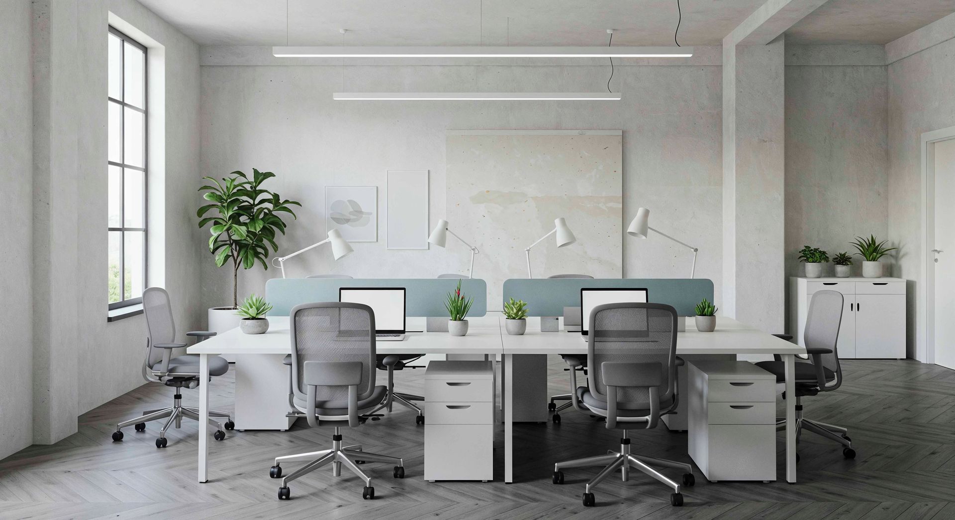 Bright office space with desks, chairs, computers, plants, and overhead lighting.