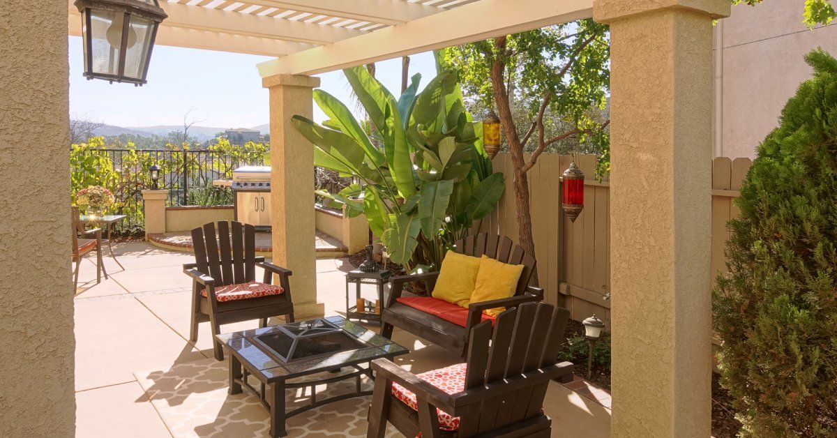 A Californian patio space overlooking a mountain view with a wooden furniture set and a firepit in the center.