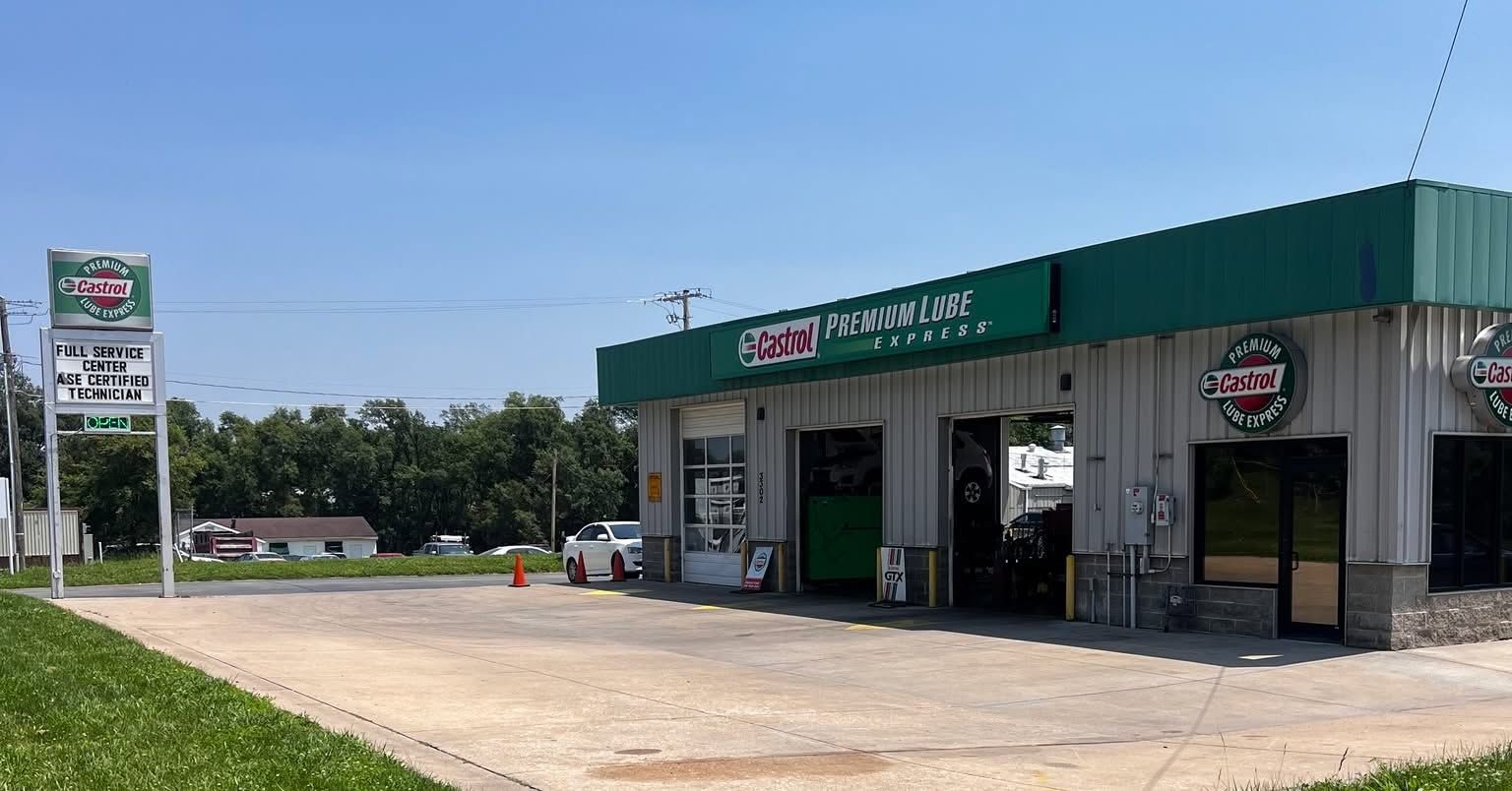 Roadside convenience store with green awning and gas pumps under a clear blue sky. | Castrol Pro-Lube of St. Joe