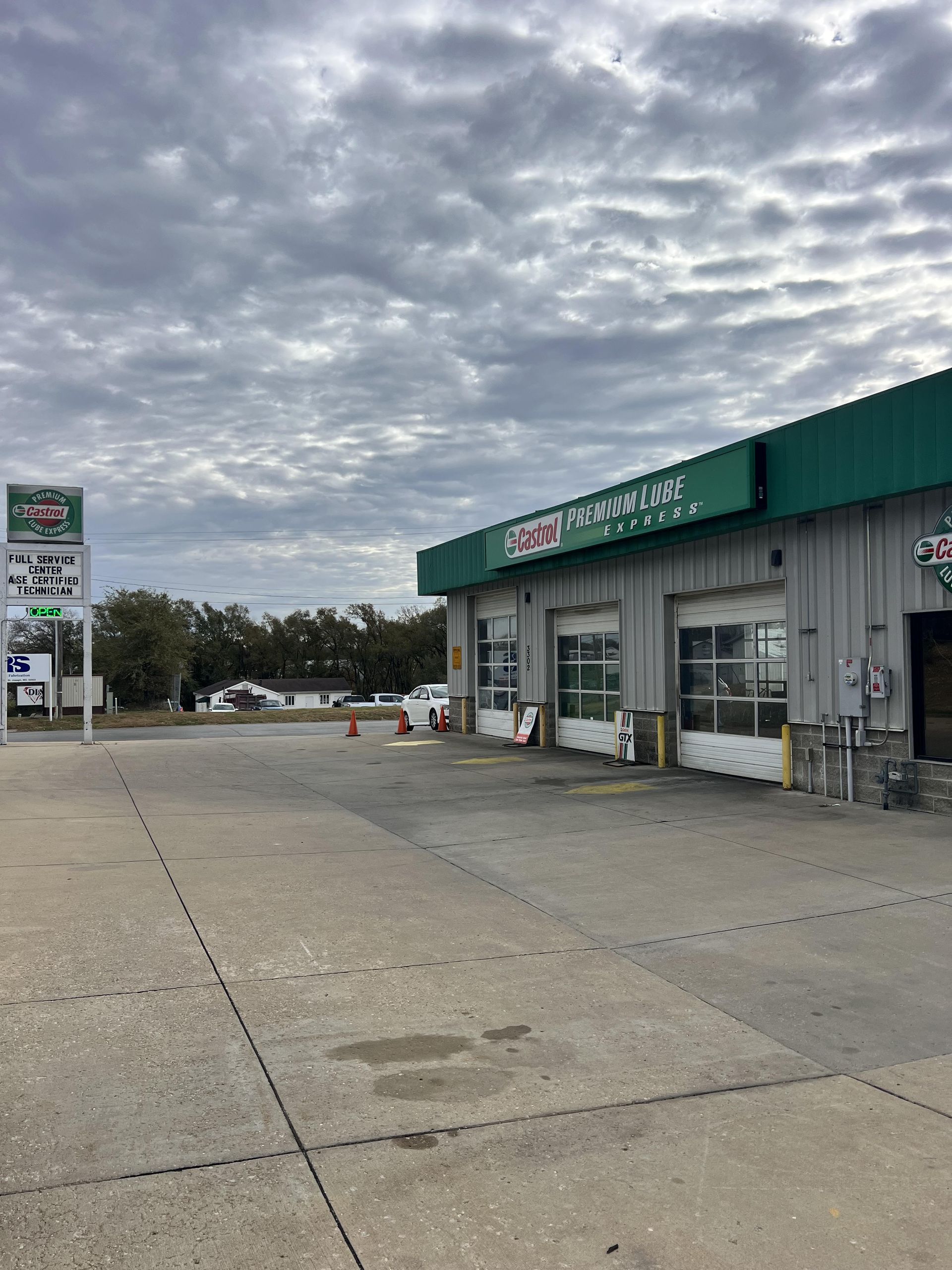 Convenience store with green awning and gas station pumps under a cloudy sky | Castrol Pro-Lube of St. Joe