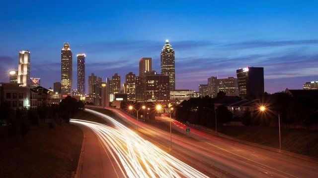 A blurry picture of a city skyline at night with a highway in the foreground.