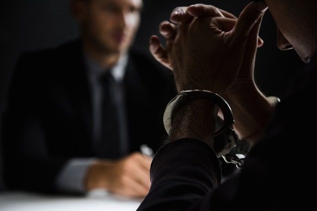 A man in handcuffs is talking to a man in a suit.
