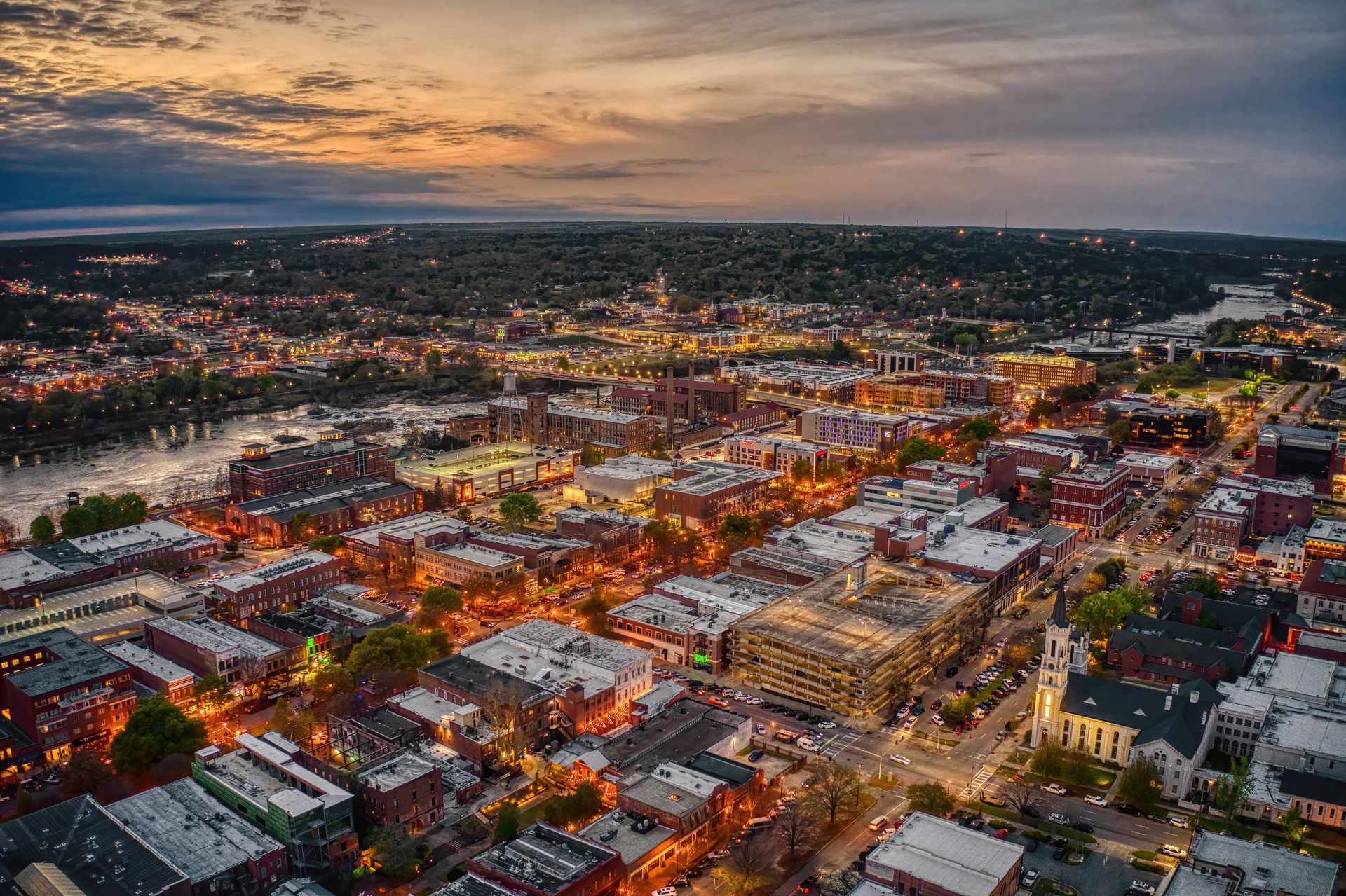 An aerial view of a city at night with a river in the background.