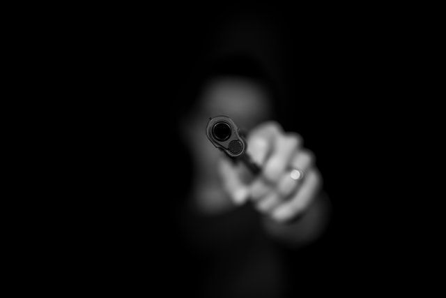 barrel of gun being pointed at viewer by an anonymous person