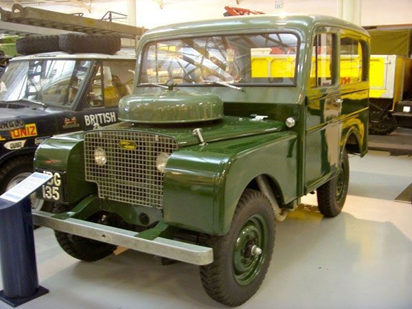 Vintage green military truck on display in a museum, with another vehicle behind it