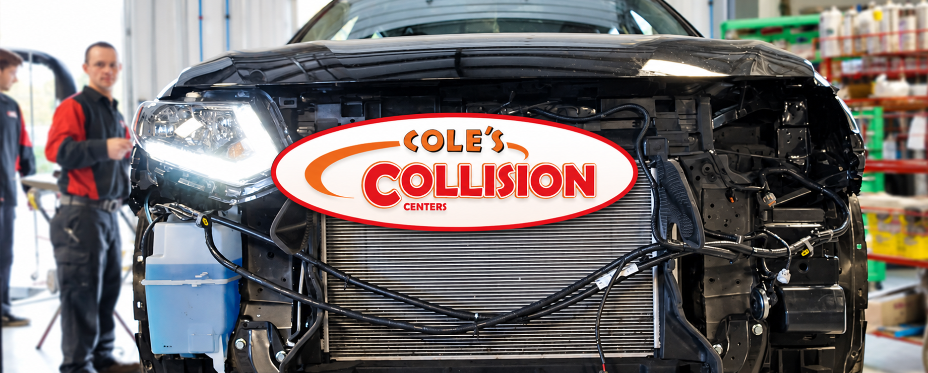 Damaged black car with a “Bob’s Collision” sign in a repair shop, front view.