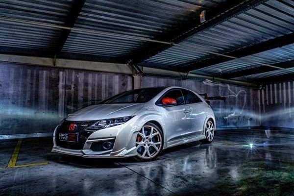Silver sports car parked in a wet garage, reflecting dramatic lights on the floor