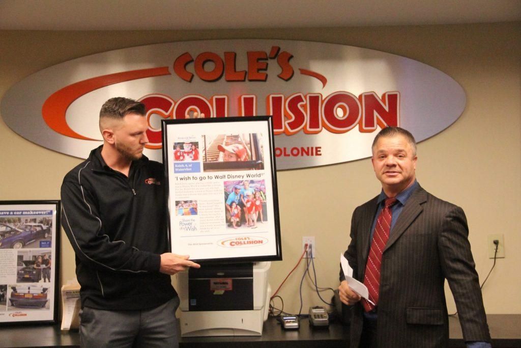 Two men in a radio studio hold a framed certificate in front of a COLE'S COLLISION sign.