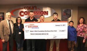 Group holding oversized donation check at Collision event, standing in front of a branded backdrop.