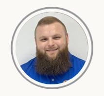 Smiling bearded man in a blue shirt, shown in a circular profile photo with a light gray background