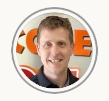 Portrait of a smiling man in a circular frame, with an orange sign in the background