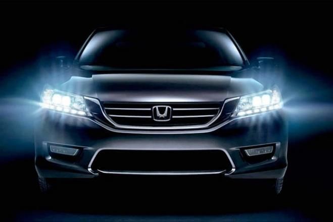 Front view of a black Honda sedan with bright headlights against a dark background