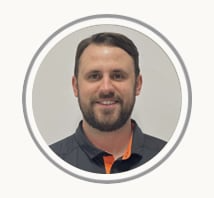 Smiling man in a dark gray shirt with orange trim, shown in a circular profile photo