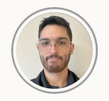 Portrait of a man with glasses and a short beard, centered in a circular frame against a plain background