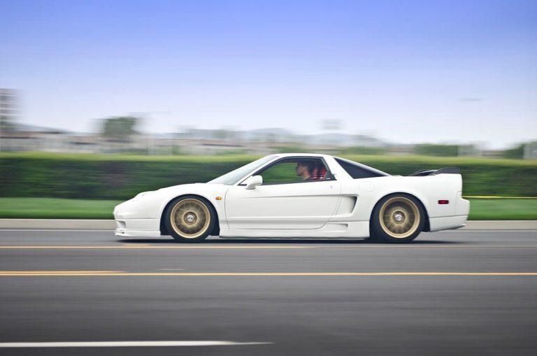 White sports car speeding on a road with motion-blurred background