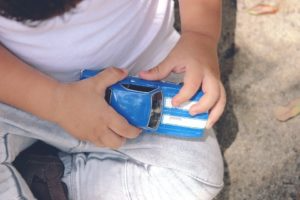 Child holding a blue toy car close-up on a concrete surface