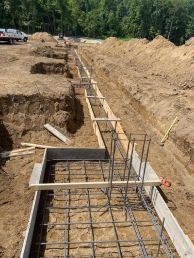 Trenched construction site with rebar and wooden forms for a concrete foundation in a dirt excavation