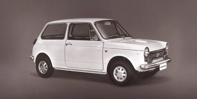 White vintage compact car on a studio backdrop, shown in side view.