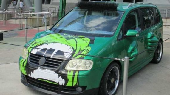 Green car with black-and-white front graphics parked outdoors