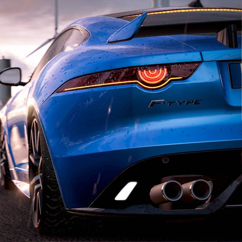 Rear view of a blue Jaguar F-Type sports car with glowing taillights on a road at sunset