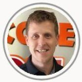 Smiling man in a circular profile photo with a light background and orange lettering behind him