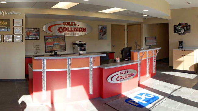 Collision repair shop reception desk with red counter, beige walls, and seating area
