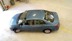 Blue sedan parked in a marked indoor lot, viewed from above